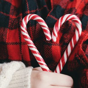 person holding candy cane heart with red and black plaid background