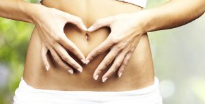 healthy woman doing heart symbol on her belly button at outdoor